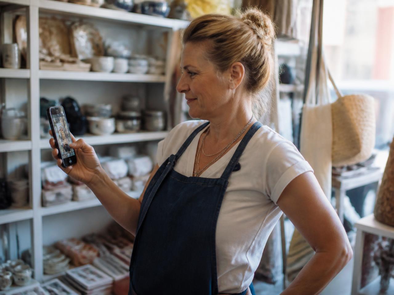A small business owner watching her own video ad play on a screen inside her shop